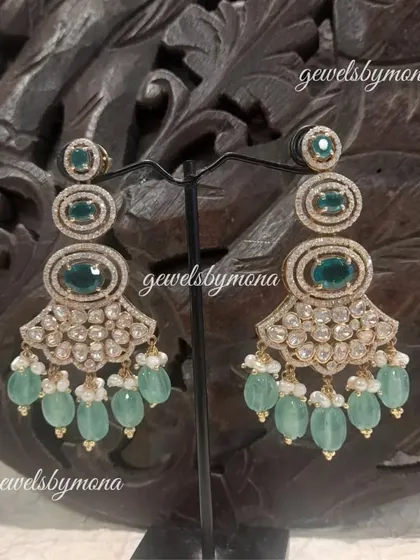These elaborate chandelier earrings feature multiple tiers of polkis and are finished with soft green bead drops. The design is grand and opulent, perfect for a bride or a wedding guest.