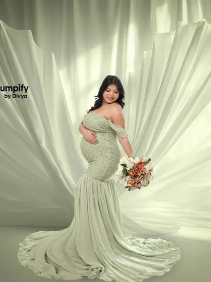 Using flowing fabric to create a sense of movement and drama. The mom-to-be holds a bouquet while the light green fabric billows behind her, creating a stunning effect.