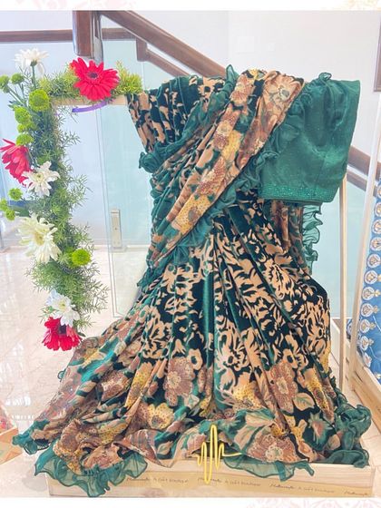 This luxurious velvet saree is draped on a custom stand with a floral garland, showcasing its rich texture and pattern as part of a bride's trousseau collection.
