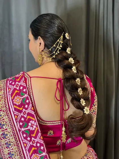 A side view of a dramatic pull-through braid, showing the volume and texture. The floral pins and hair chain add layers of detail to this beautiful bridal hairstyle.
