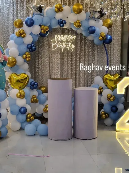 A fun Cocomelon theme birthday party decoration for a two-year-old. This setup includes a character cutout, a "Happy Birthday" neon sign, a light-up number '2', and a blue and gold balloon arch.