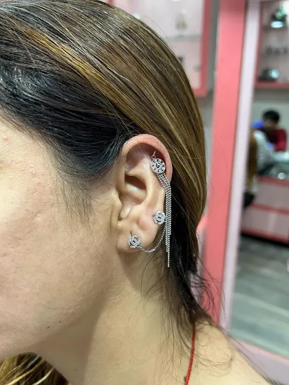 A unique and intricate ear stack featuring a triple-chain hanging that connects multiple piercings, creating a stunning web of silver.