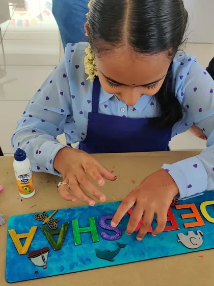 A close-up of a young artist carefully placing letters on her personalized nameplate during a birthday party.