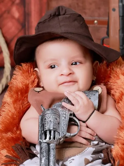 A close-up of our tiny wrangler, complete with a cowboy hat and a toy pistol. We love capturing the details that make each themed shoot special.