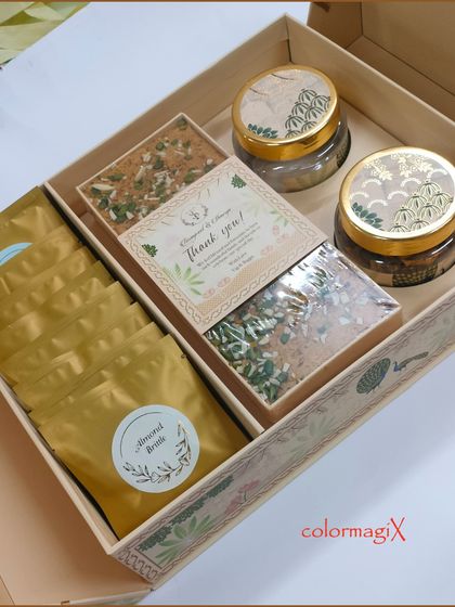 A close-up of the contents of our wedding favor box, including almond brittle pouches and jars of premium dry fruits, accompanied by a heartfelt thank you note.