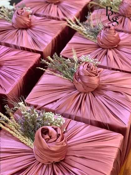 An example of our intricate fabric wrapping technique. This dusty rose satin fabric is meticulously pleated and folded into a central rose knot, accented with delicate dried flowers for a soft, romantic finish.