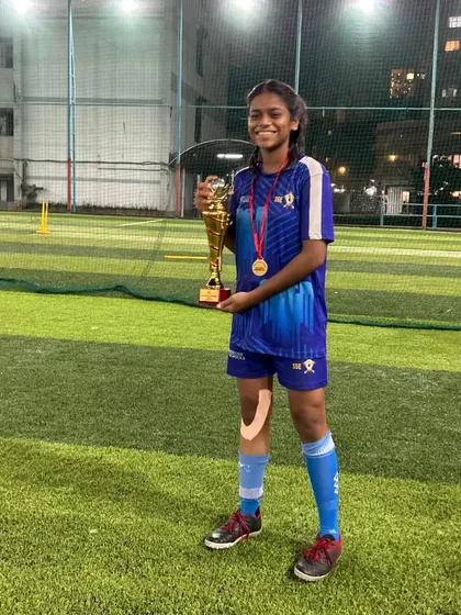 A triumphant player from our U17 girls team holds the championship trophy. Her smile reflects the hard work and dedication that led to this victory.