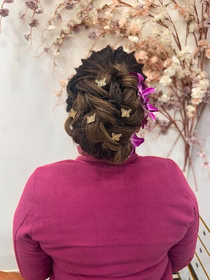 A different angle of the beautiful braided updo, showing the intricate weaving and the placement of the butterfly clips and fresh flowers.