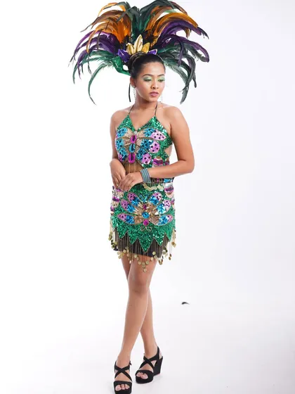 A vibrant carnival-style costume available for rent. This look features a sequined butterfly top and a massive feathered headdress, perfect for a high-energy fashion or portfolio shoot.
