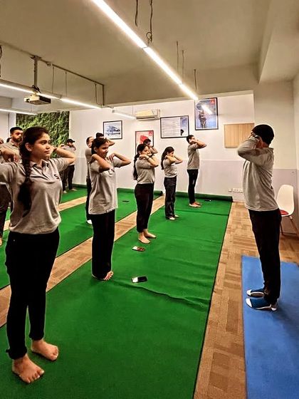 Employees participating in a standing warm-up exercise during our corporate yoga session. These simple movements help relieve shoulder and neck tension.