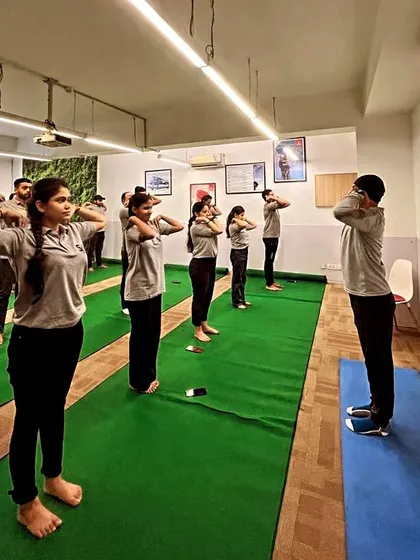 Employees participating in a standing warm-up exercise during our corporate yoga session. These simple movements help relieve shoulder and neck tension.