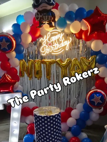 A Captain America-themed 7th birthday party. The decor features a balloon arch in red, white, and blue, Captain America's shield, a neon sign, and a marquee number.