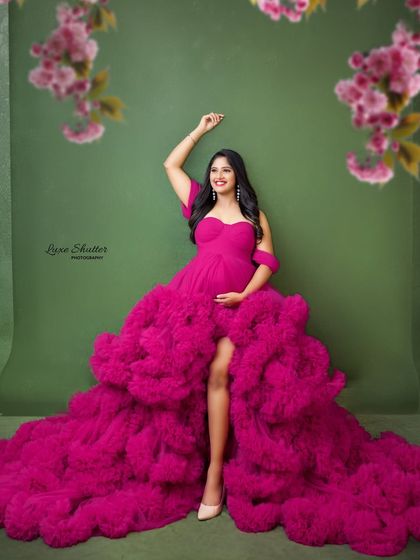 Glowing and growing in this beautiful pink gown. The vibrant color and playful ruffles add a sense of fun and celebration to this maternity portrait.