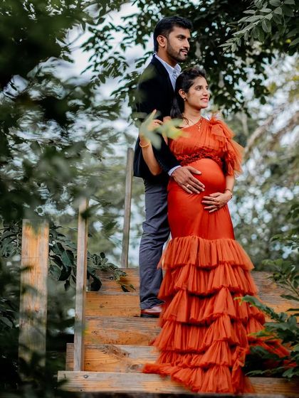 A romantic shot of a couple in a lush, green setting. The Bronze gown's tiered skirt adds beautiful texture and movement.