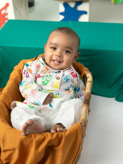 A close-up of a baby's happy, tongue-out smile during his first Holi photoshoot.