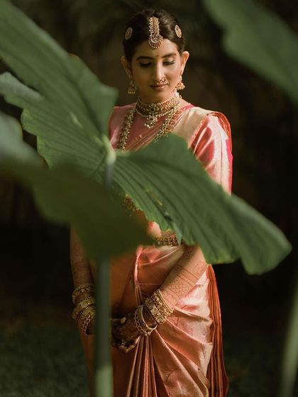 An artistic shot of the bride amidst lush greenery, looking ethereal in her saree and henna.