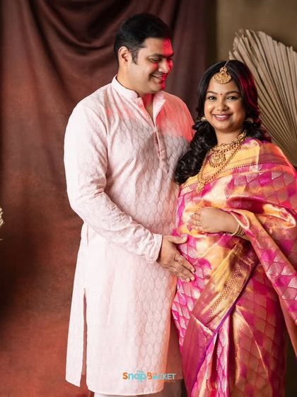 This couple is glowing with happiness. Her magnificent pink and gold silk saree looks so regal in our studio. It’s a perfect way to celebrate this special time with traditional elegance.