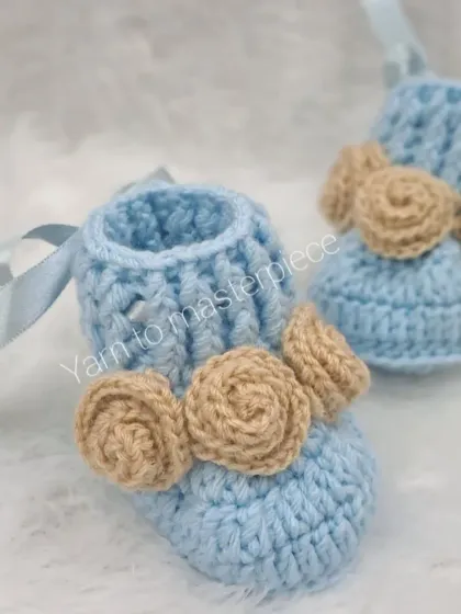 These baby blue booties are adorned with three delicate, hand-rolled roses in a contrasting beige color, creating a beautiful and unique look.