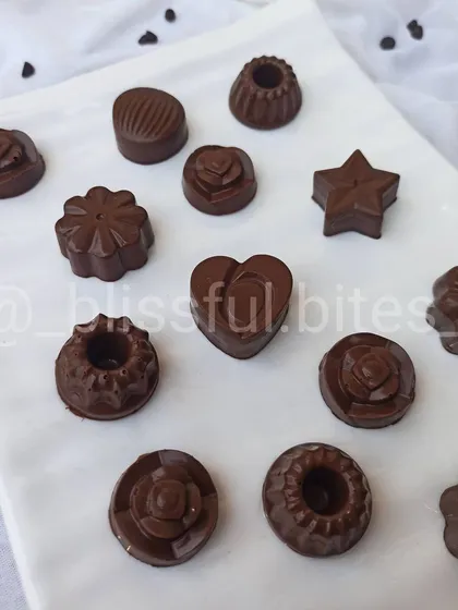 A glimpse of my homemade chocolate selection, perfect for gifting or a personal indulgence. You can see the different shapes and moulds I use, from hearts to flowers, each filled with flavours like hazelnut, almond, and caramel.