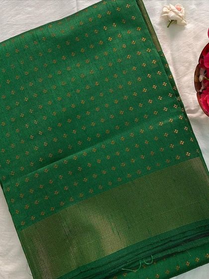 The semi raw silk saree in a lush green color with gold butti. The texture and sheen of the fabric make it feel truly luxurious.