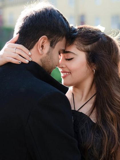 A soft and tender close-up of the couple. The backlight highlights the bride's hair as she smiles, creating a warm and dreamy portrait.