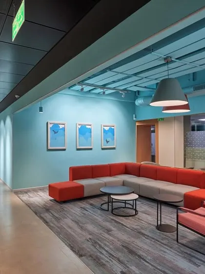 A spacious lounge area with a large L-shaped sofa in red and grey. The pastel blue walls and ceiling create a calm and serene atmosphere.