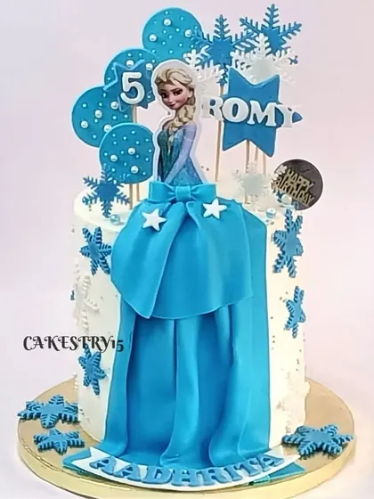 A single-tier Elsa-themed cake. This design features a fondant Elsa figure in her iconic blue dress, surrounded by edible snowflakes, perfect for a 5th birthday.