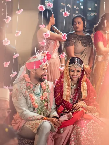An artistic shot of the couple at the mandap, viewed through a soft foreground, creating a dreamy, intimate feel.