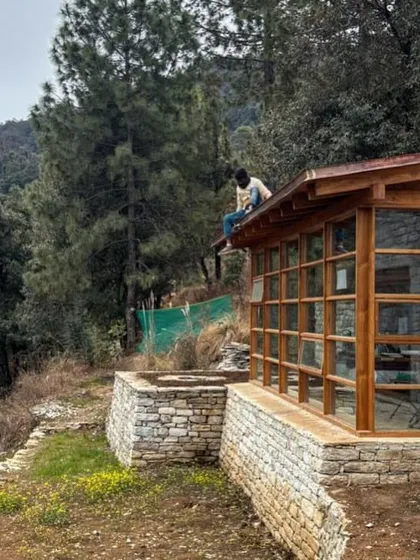 This structure in Uttarakhand, with its expansive glass and timber facade, is nestled into the hillside. The design uses a combination of local stone for the foundation and wood for the upper levels, creating a dialogue between the building and the dense pine forest.