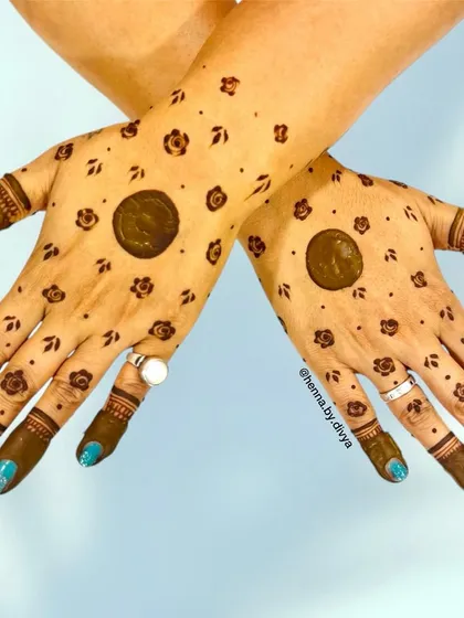 A playful and minimal design with a central filled circle, or "chand," surrounded by small floral bootis. This is a traditional style that remains popular for festivals like Teej and Karva Chauth.