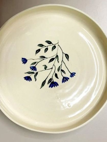 This hand-painted ceramic plate features a simple yet elegant floral design. Each piece is lovingly crafted to be one-of-a-kind, perfect for elevating your dining experience or home decor.