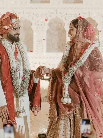 A candid moment of the couple holding hands and smiling at each other during their wedding ceremony.