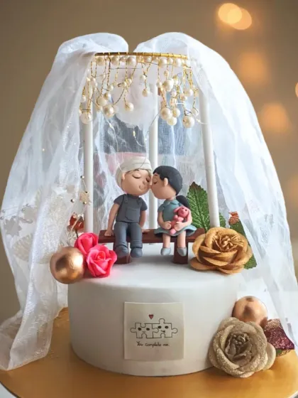 This romantic anniversary cake captures a tender moment, with detailed fondant figures of a couple sharing a kiss under a delicate, draped veil accented with pearls. It’s a beautiful, personalized story told in sugar art.