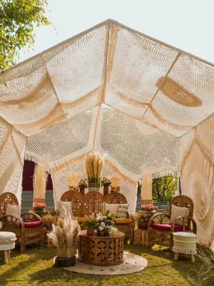 Seating pretty in boho bliss. This macrame tent with cane furniture and earthy decor creates a beautiful and cozy setting for a Mehendi, where every cushion holds a tale.