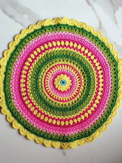 A top-down view of the Viola mandala, showing its perfectly circular shape and the variety of stitches used to create the pattern, including puff stitches and open lacework.