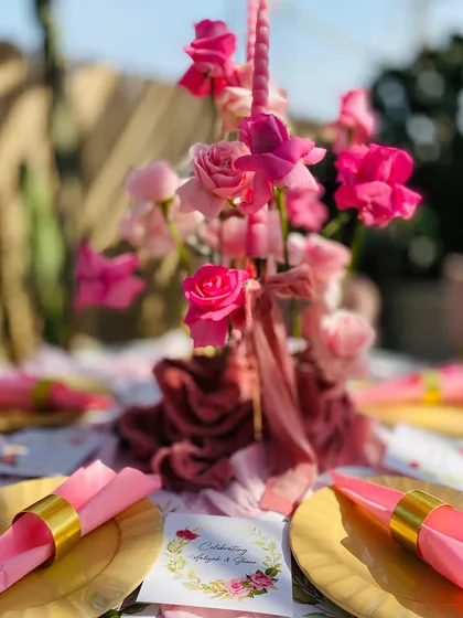 The elegant tablescape, with gold plates, pink napkins, and a beautiful floral centerpiece, setting the tone for a special celebration.