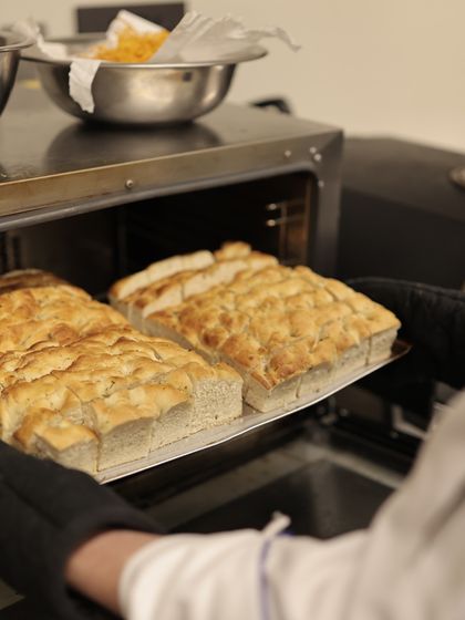 Freshly baked focaccia bread coming straight out of the oven, filling the air with an irresistible aroma.