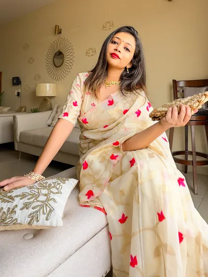 For Subho Bijoya, I chose to stick to the traditional white and red color theme with this modern Jamdani saree. It features beautiful zari and lotus motifs, which I complemented with lotus jewelry and a jute clutch, an element true to Bengali culture.