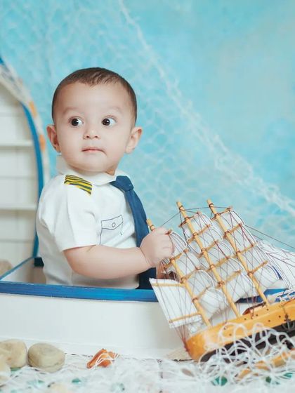 A curious little sailor looks out from his boat. These themed shoots are designed to be engaging and fun for your baby.