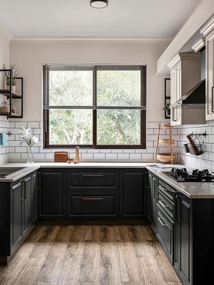 A kitchen from the 'Under the Sun' villa project, featuring a classic black and white theme. The large window overlooks the surrounding greenery, making the space feel connected to nature.