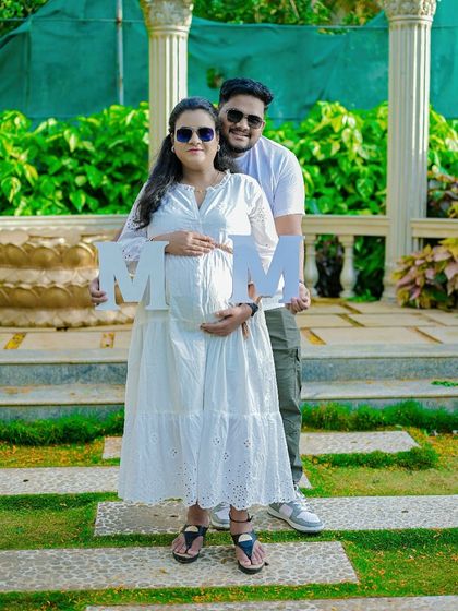 A fun and modern outdoor portrait. The couple holds up letters, adding a personal and creative touch to their pregnancy announcement photo.