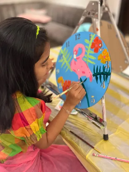 Another young participant deeply engaged in painting her flamingo clock. I love seeing the focus and creativity that art brings out in children.