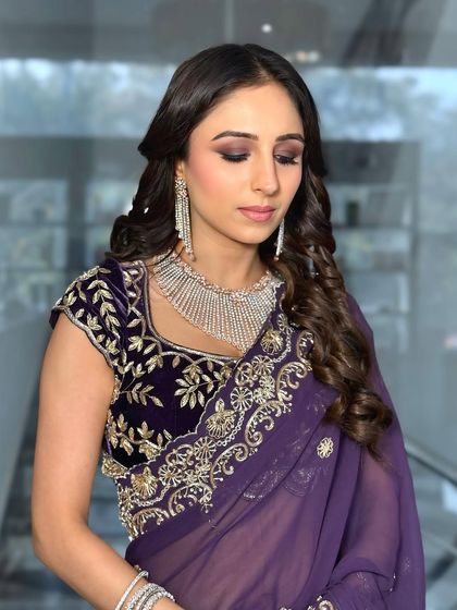 A beautiful guest ready for a chowki event. The purple smokey eye and soft curls create an elegant and sophisticated look.