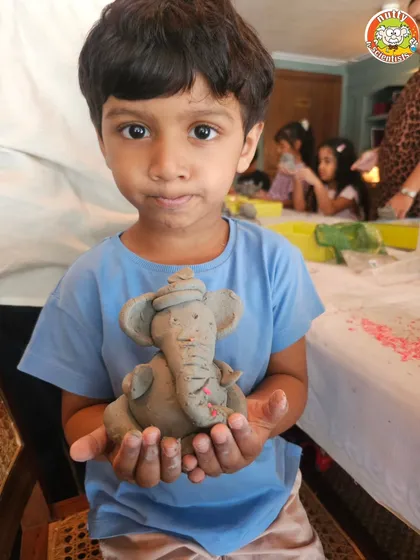 This little artist holds his finished Ganesha idol, a perfect blend of personal creativity and traditional form.