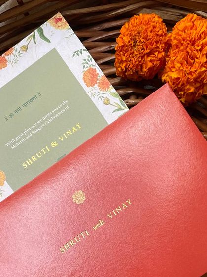 The bold red envelope paired with the green and marigold invitation card. This color combination is vibrant, celebratory, and perfectly suited for an Indian wedding.