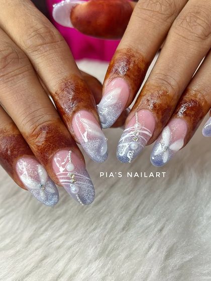 A modern take on bridal nails. This custom set features a soft blue glitter ombre with delicate white hand-painted art and 3D floral details, designed to match the bride's unique style.