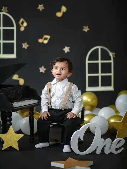 A classic portrait for a first birthday. Dressed in smart suspenders, this little boy looks like a true gentleman in our piano-themed shoot.