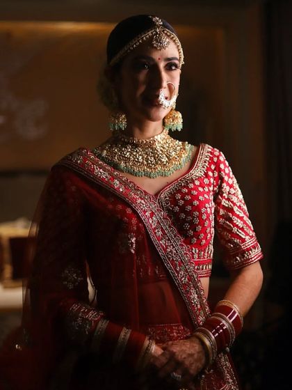 A classic bridal portrait, with soft lighting highlighting the bride's features and her red and green jewelry.