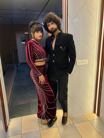 A posed shot of the two models from the perfume campaign. The contrast between the red velvet and the black jacket creates a visually dynamic and luxurious image for the brand.
