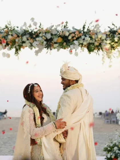 Another shot of the couple under the floral arch, with petals showering down. The bride's makeup remains flawless and beautiful throughout the celebration.